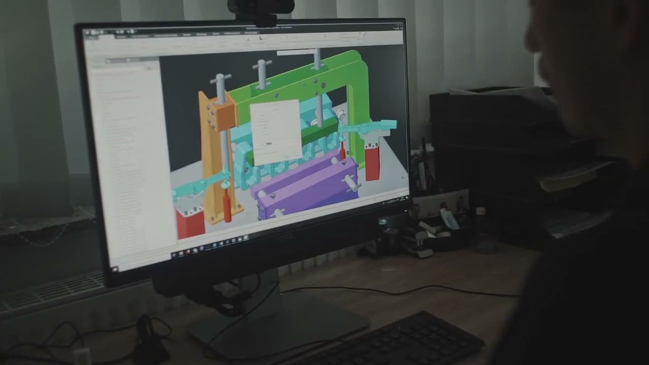 An engineer at a CAD workstation, a drawing open in a workshop, two engineers building a robot, a technician repairing a machine